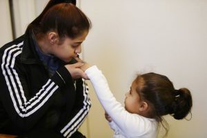 Nelyan Velazquez besa la mano de su hija, Nahira Meléndez, en su habitación de hotel en el barrio de Brooklyn de Nueva York, donde viven cuatro meses después de perder su casa en Puerto Rico en el huracán María. Foto: Frank Franklin II / AP.