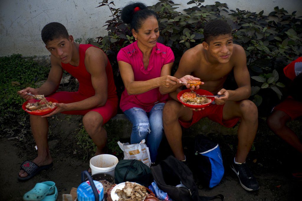 Nalis Mendoza corta un tomate mientras da de comer a sus hijos, que participan en el torneo amateur de lucha de Chicharrones, Santiago de Cuba. Foto: Ramón Espinosa / AP.