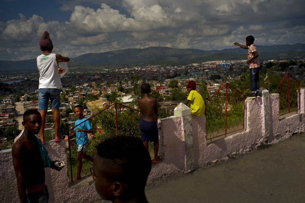 Luchadores de provincias del este y el centro de Cuba descansan junto a niños locales que juegan con papalotes. Foto: Ramón Espinosa / AP.