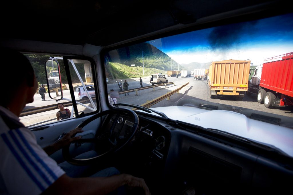 Carlos Del Pino conduce su camión cargado con arroz a granel, detrás de otros camiones de grano, mientras sale del puerto bajo la escolta de la Guardia Nacional Bolivariana venezolana para proteger de los saqueadores el convoy que transporta el arroz mientras cruzan Puerto Cabello, Venezuela. Foto: Fernando Llano / AP.