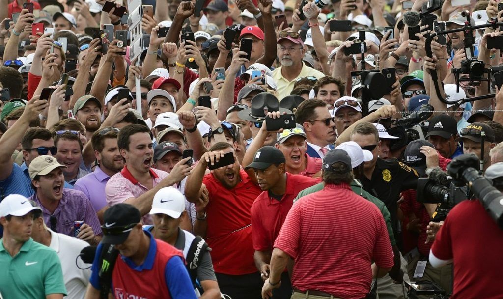 Tiger Woods, en el medio, y Rory McIlroy, abajo al extremo izquierdo, emergen entre el público durante el 18vo hoyo del Campeonato del Tour en Atlanta, el 23 de septiembre de 2018. (AP Foto/John Amis)