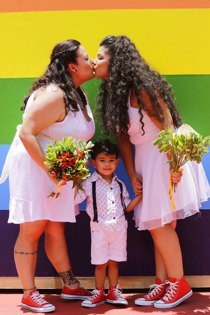Thais Lococo Hansen, de 32 años, izquierda, y su pareja Catarina Brainer, de 28 años, se besan después de contraer matrimonio en medio de su hijo Pietro, de tres años, durante una ceremonia colectiva de parejas del mismo sexo en Sao Paulo, Brasil, el sábado 15 de diciembre del 2018. (AP Foto/Nelson Antoine)