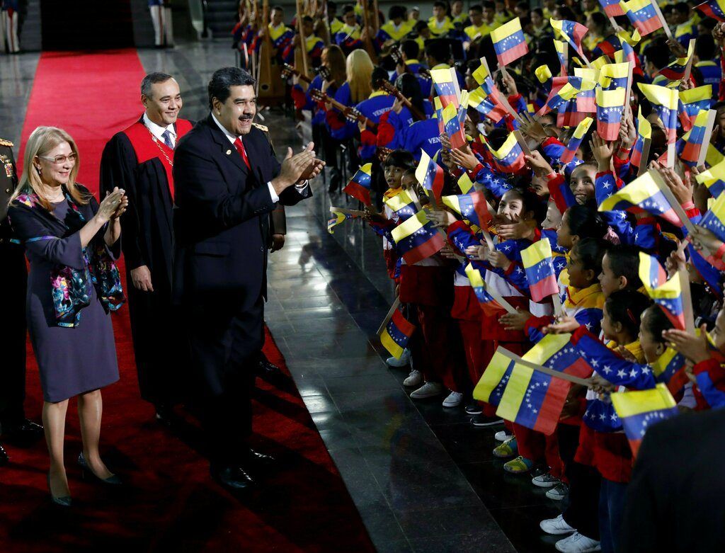 Nicolás Maduro, y la primera dama, Cilia Flores, se detienen para saludar a los niños que agitan la bandera al llegar a la ceremonia de juramentación en el Tribunal Superior de Justicia. Foto: Ariana Cubillos / AP.