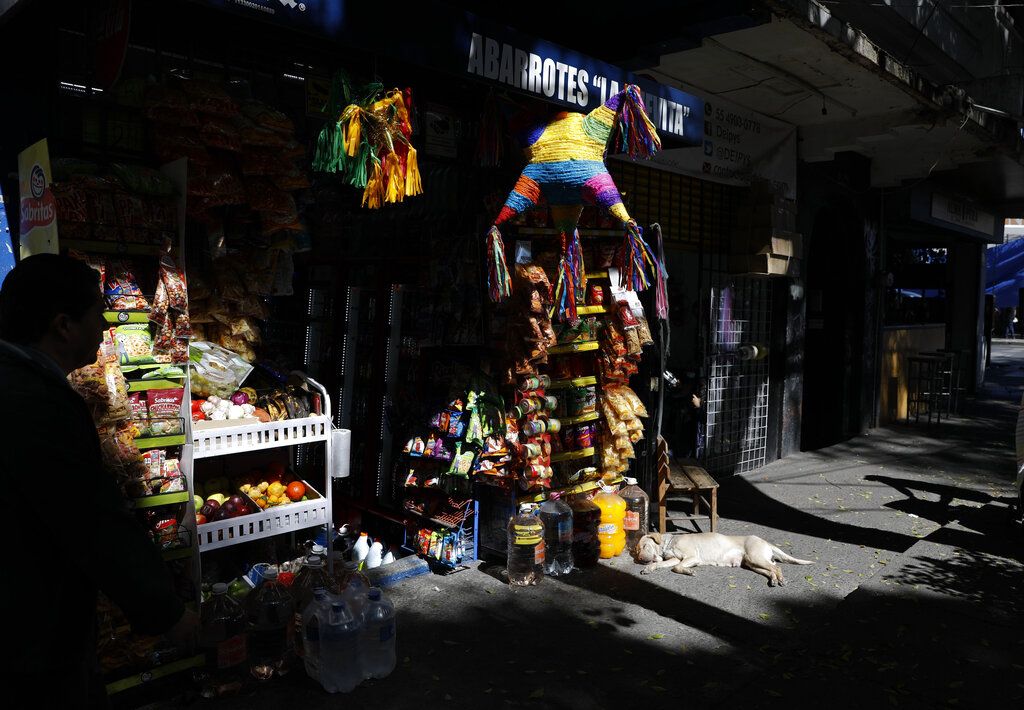 Un perro acostado frente a una tienda con piñatas en la colonia Roma Sur de la Ciudad de México.(Foto AP/Rebecca Blackwell)
