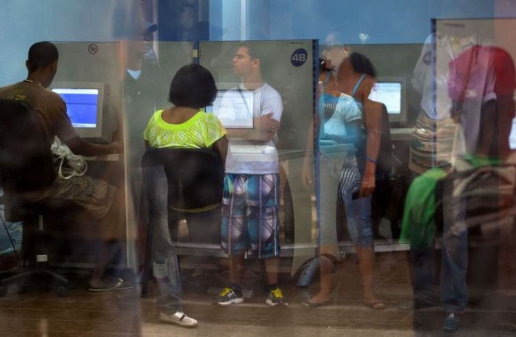 People reflected in the window line up at a post office as they wait to use the Internet service in Havana, Cuba, on May 28, 2013. / Photo: Ramon Espinosa/Associated Press.
