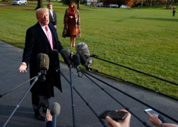 Donald Trump speaks with the press when leaving the White House on November 21, 2017 en route to Mar-a-Lago in Palm Beach, Florida, for Thanksgiving Day. First Lady Melania Trump and their son Barron wait in the background. Photo: Evan Vucci / AP.