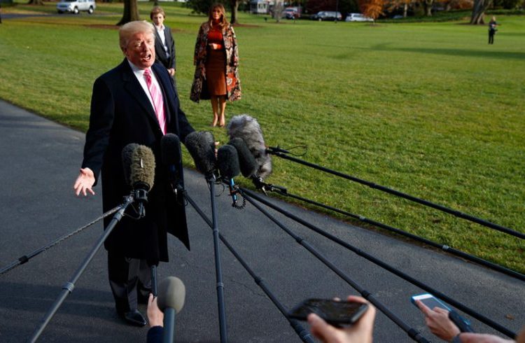 Donald Trump speaks with the press when leaving the White House on November 21, 2017 en route to Mar-a-Lago in Palm Beach, Florida, for Thanksgiving Day. First Lady Melania Trump and their son Barron wait in the background. Photo: Evan Vucci / AP.