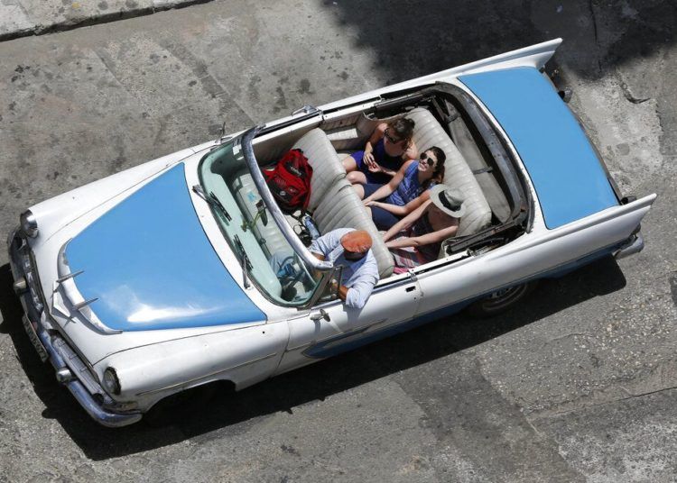 In this picture taken on May 13, 2015, tourists stroll in a classic convertible in Havana. Photo: Desmond Boylan / AP.