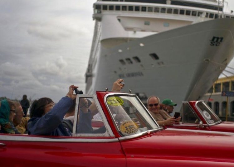 Tourists touring Havana pass in front of a cruise ship docked in the port of the Cuban capital. Photo: Ramón Espinosa / AP.