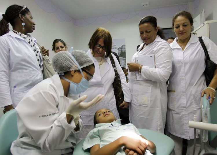 Cuban doctors observe a dental procedure during a training session at a health clinic in Brasilia. Photo: Eraldo Peres / AP.