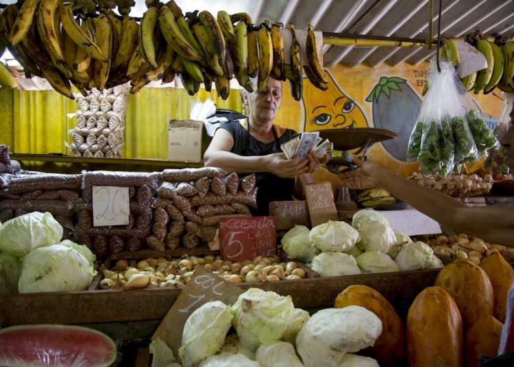 A saleswoman counts money after selling some vegetables to a customer at her stand in Havana. Photo: Ismael Francisco / AP / Archive.