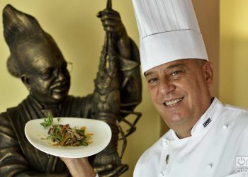 Chef Eddy Fernández, president of the island’s Federation of Culinary Associations and a tireless defender of Cuban cuisine. Behind, a statue of chef Gilberto Smith, founder of the Federation and one of the essential figures of culinary art on the island. Photo: Otmaro Rodríguez.