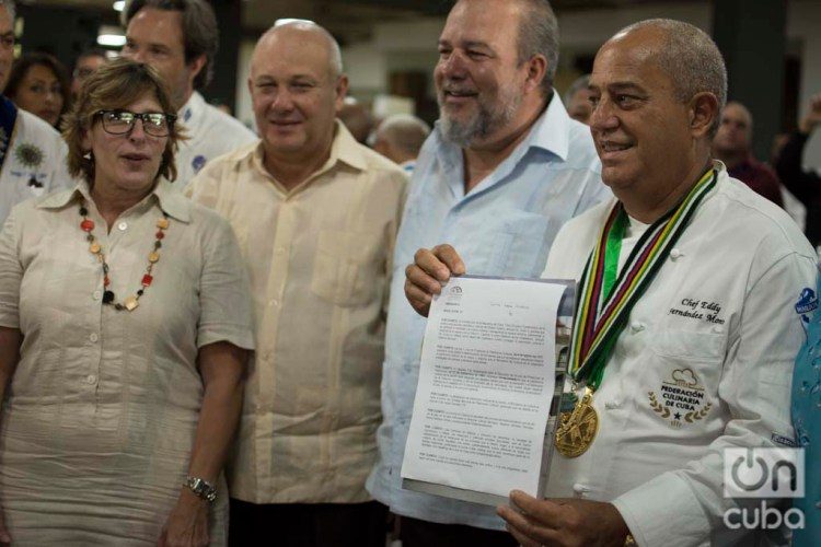 Chef Eddy Fernández (r), president of the Culinary Federation of Cuba, shows the document that accredits Cuban cuisine as national Cultural Heritage. Next to him, Cuban Minister of Tourism Manuel Marrero (second to the right) and Gladys Collazo, president of the National Cultural Heritage Council (l), among other personalities. Photo: Otmaro Rodríguez.
