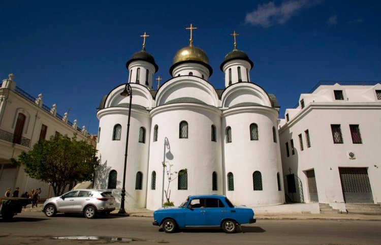 A Moskvitch car from the Soviet era circulates in front of the Russian Orthodox Cathedral in Havana. Photo: Ismael Francisco / AP.