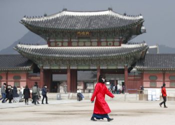 A woman with her mouth covered by a mask walks in front of Gyeongbokgung Palace, one of South Korea's best known monuments in Seoul, on February 22, 2020. (AP Photo/Lee Jin-man)