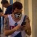 A Cuban checks his cell phone using a facemask in Havana, as a protection measure against the COVID-19 pandemic. Photo: Otmaro Rodríguez.
