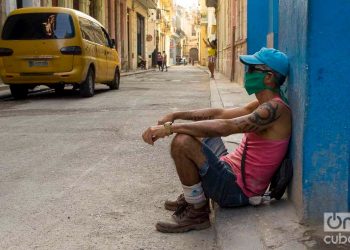A man sitting on a sidewalk in Havana, with a facemask as a measure of protection against the coronavirus pandemic. Photo: Otmaro Rodríguez.