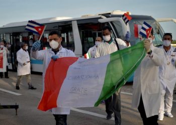 Cuban doctors wave Cuban and Italian flags after their arrival in Havana from Europe this Monday. Photo: Yamil Lage/EFE