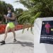A person wearing a mask walks along Miami Beach, Florida, on Saturday, July 4, 2020. (AP Photo/Wilfredo Lee)
