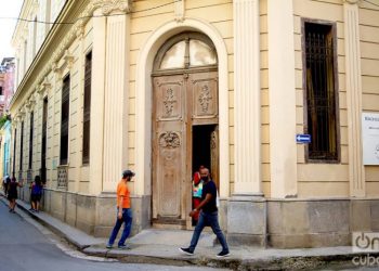 Some people pass in front of an outer door in Havana. Photo: Otmaro Rodríguez.