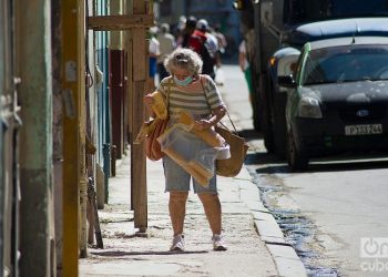 An elderly woman with bread and other purchases walks down a street in Havana during the outbreak of COVID-19 in January 2021. Photo: Otmaro Rodriguez.