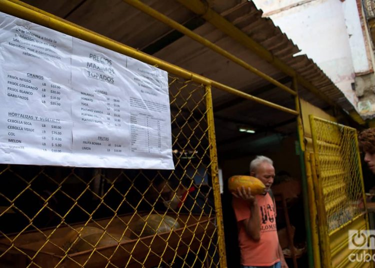 A man leaves an agricultural market in Havana with his purchases. In the foreground, the list of prices “capped” by the government. Photo: Otmaro Rodríguez.