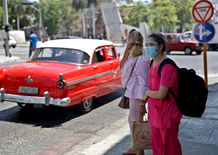 Two women wait for a taxi on a street in Havana. Photo: Yander Zamora/EFE.