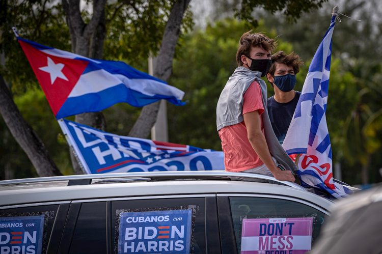 Some young people listen to the speech by former U.S. President Barack Obama, sitting on the roof of a car decorated with posters that say “Cubans with Biden Harris,” during a rally in support of the Democratic presidential candidate Joe Biden, on Campus Biscayne of Florida International University (FIU) in Miami, Florida. Photo: Giorgio Viera/EFE (Archive)