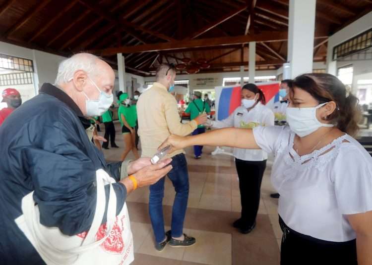 Tourism workers offer hand sanitizer gel to visitors who arrive at a hotel in Cayo Coco, Cuba, in December 2020. Photo: Ernesto Mastrascusa/EFE/Archive.