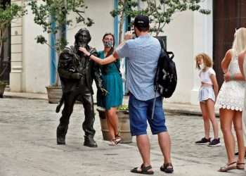 Tourists take photos next to the sculpture of the Caballero de París, in Old Havana. Photo: Ernesto Mastrascusa/EFE.