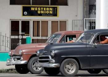 Two vintage cars pass in front of a Western Union office, in Havana, on its last day of operations in Cuba, on November 23, 2020. Photo: Ernesto Mastrascusa/EFE/Archive