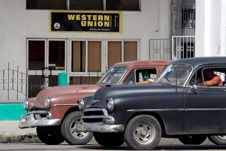Two vintage cars pass in front of a Western Union office, in Havana, on its last day of operations in Cuba, on November 23, 2020. Photo: Ernesto Mastrascusa/EFE/Archive