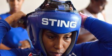 A Cuban woman boxer adjusts her headgear. Cuba