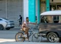 Cyclist holds on to a car so as not to have to force himself to pedal, Havana, Cuba. Photo: Otmaro Rodríguez.