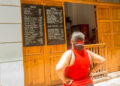 Woman looks at the prices of a MSME in Cuba