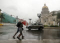 Two people walk in the rain in Havana. Economy