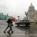 Two people walk in the rain in Havana. Economy