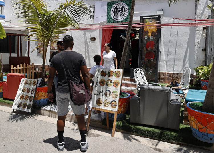 People walking past the Starcafé Restaurant in Havana. Photo: Ernesto Mastrascusa/EFE.