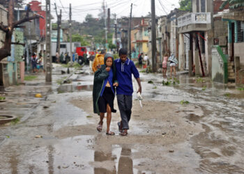 People walk along a street affected by Hurricane Melissa in Santiago de Cuba
