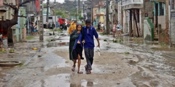 People walk along a street affected by Hurricane Melissa in Santiago de Cuba
