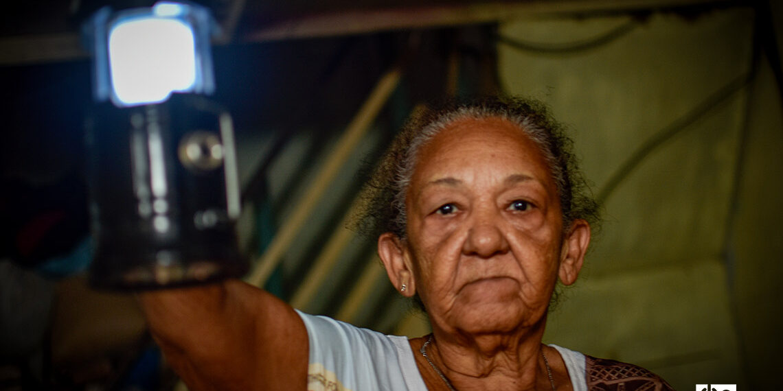 An elderly woman lights her way with a lantern during a power outage in Havana