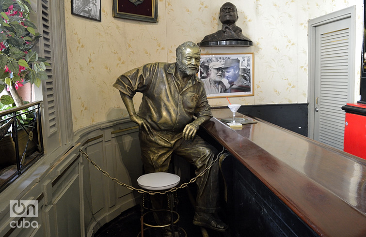 Tiene su espacio reservado eternamente en el Floridita, con uno de sus gustados daiquirís enfrente. Acodado en la barra, Ernest Hemingway observa socarrón a los visitantes del célebre bar habanero, con los ojos de bronce esculpidos por José Villa Soberón, delante de una foto suya con Fidel Castro. Foto: Otmaro Rodríguez.