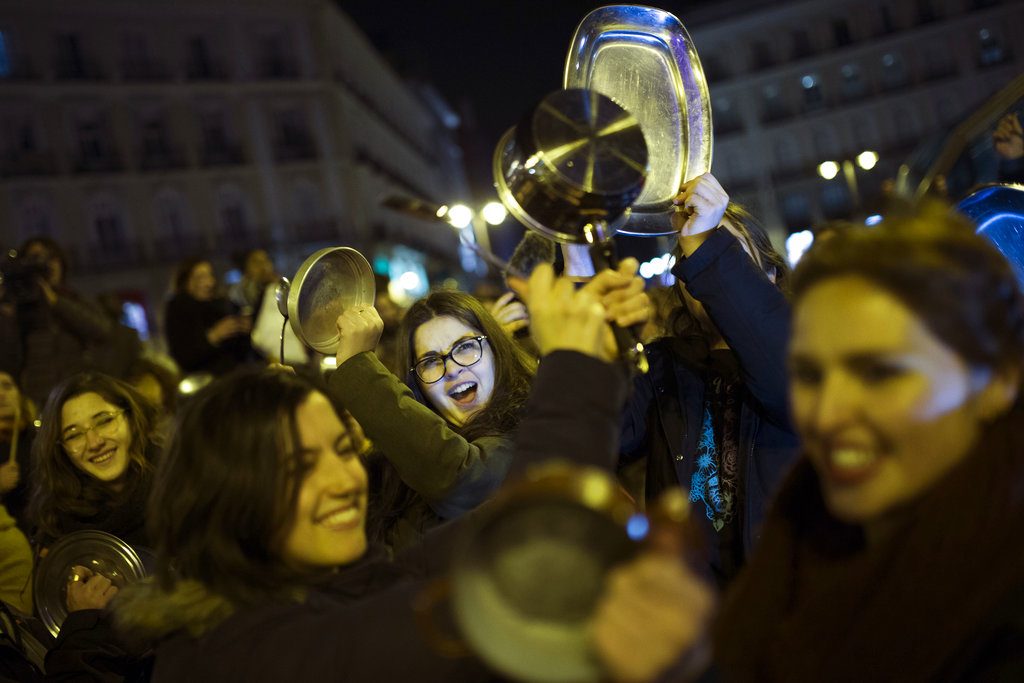 Mujeres golpeando cacerolas y sartenes mientras corean lemas durante una protesta marcando el inicio de una huelga de mujeres de 24 horas en la Puerta del Sol de Madrid, en la madrugada del jueves 8 de marzo de 2018. (AP Foto/Francisco Seco)