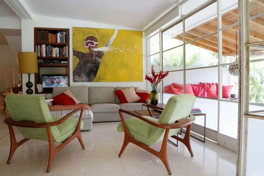 En la sala de estar íntimamente escalonada de Katharina Voss y Enrique Arias, sillones cubanos de mediados del siglo XX enmarcan una pintura de Alejandro Campins. Foto: Carlos Otero.