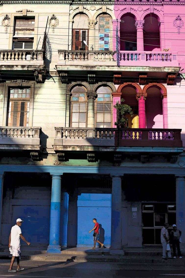 Early morning on Infanta Street in Centro Havana. The pink house on the right is newly painted, in Havana one sees many homes painted alongside ones that aren't. Cubans are almost exclusively owners of their homes and responsible for maintenance. Paint is expensive and hard to come by. In this way, painted homes are becoming an indicator of haves and have-nots.  / Photo: Lisette Poole for Newsweek