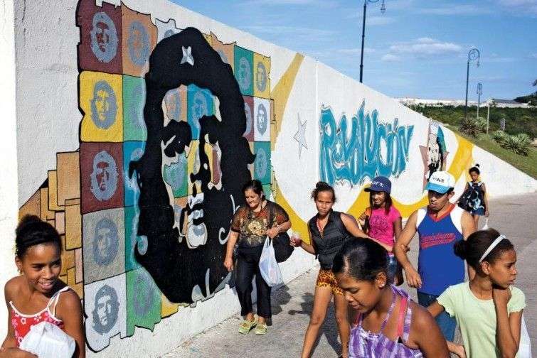 On a Sunday afternoon, kids walk by a Ché mural in Old Havana, on the side of the tunnel that leads to Havana’s eastern beaches. They've just gotten off the bus from the beach. / Photo: Lisette Poole for Newsweek