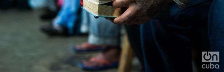 Un cubano sostiene una biblia mientras escucha la misa. Foto: Irina Dambrauskas.
