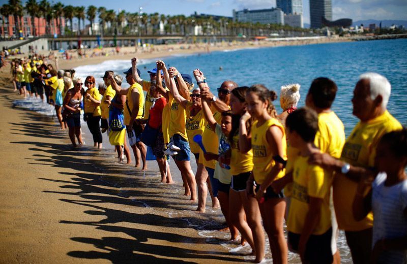 Una cantidad de personas forman una cadena humana durante una protesta contra el turismo desbordado en una playa de Barcelona el 12 de agosto del 2017. (AP Photo/Manu Fernández, File)