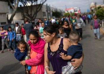 Migrantes que quieren ingresar a Estados Unidos pidiendo asilo caminan hacia el lugar donde se reunirán con abogados, el viernes 27 de abril en Tijuana, México. Foto: Hans-Maximo Musielik / AP.