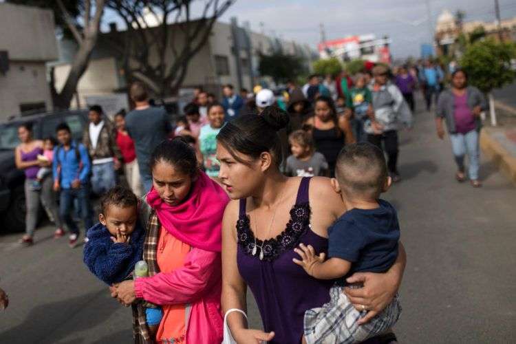 Migrantes que quieren ingresar a Estados Unidos pidiendo asilo caminan hacia el lugar donde se reunirán con abogados, el viernes 27 de abril en Tijuana, México. Foto: Hans-Maximo Musielik / AP.